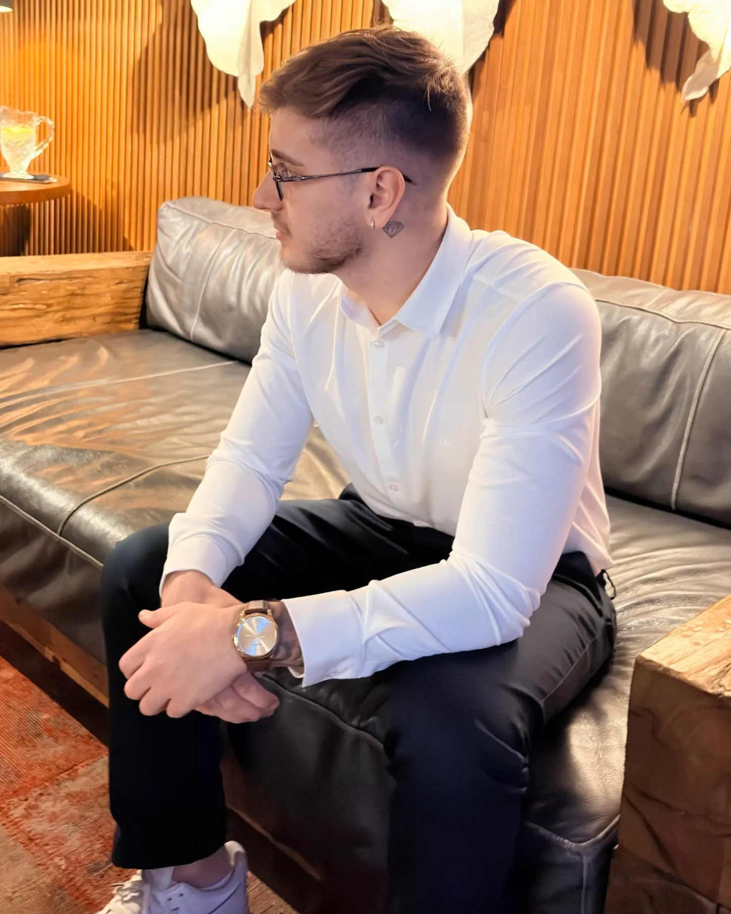Motter in profile, seated with hands clasped, looking to the side